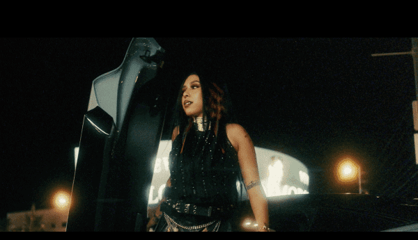 Stylish woman with tattoos and braided hair standing beside a luxury car at night, showcasing urban fashion and nightlife vibes.